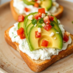 Toast with creamy avocado slices, diced tomatoes, and cream cheese on a plate.